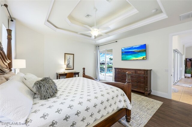 bedroom with a tray ceiling, access to exterior, ceiling fan, and hardwood / wood-style flooring