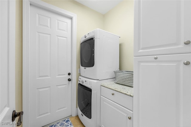 laundry area featuring stacked washer / drying machine and light tile patterned flooring