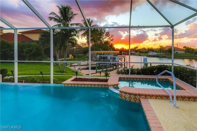 pool at dusk featuring a water view, a yard, a lanai, and a patio area