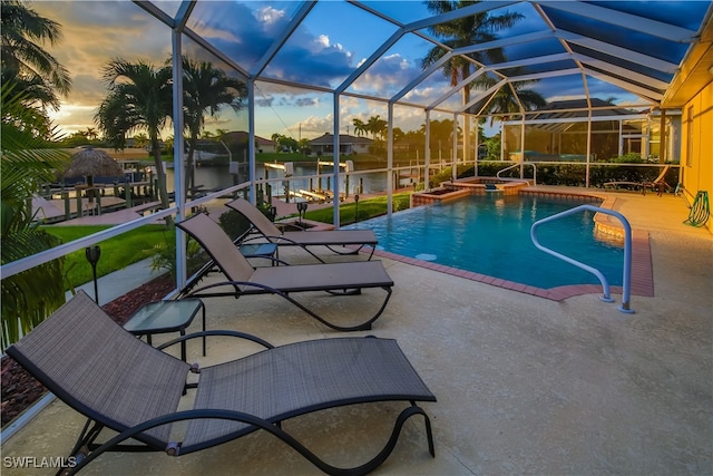 pool at dusk featuring glass enclosure, a water view, and a patio area