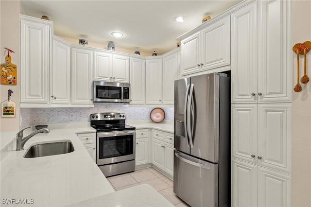 kitchen with sink, appliances with stainless steel finishes, white cabinets, and light tile patterned floors