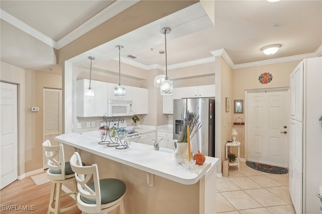 kitchen featuring kitchen peninsula, a kitchen bar, white appliances, and white cabinetry