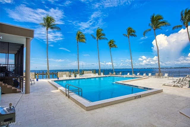 view of swimming pool featuring a water view and a patio area