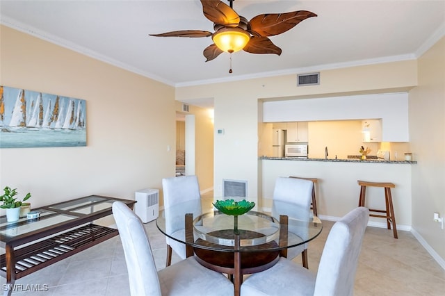 dining area featuring ceiling fan, light tile patterned floors, and crown molding