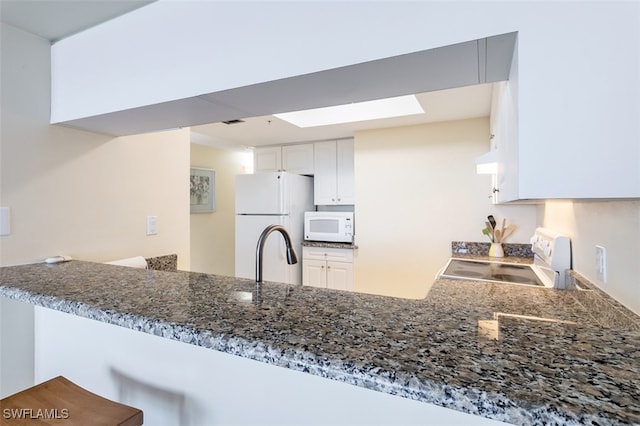 kitchen featuring ventilation hood, white appliances, white cabinetry, and kitchen peninsula