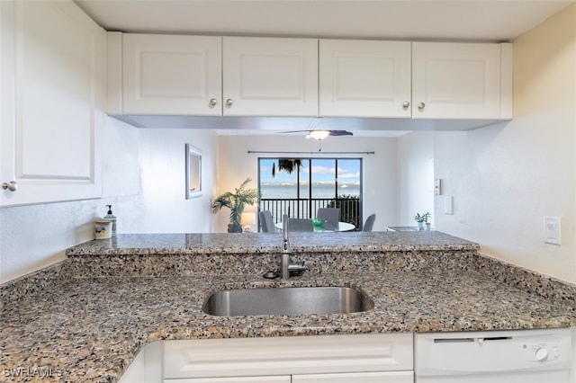 kitchen with white dishwasher, white cabinetry, light stone counters, and sink