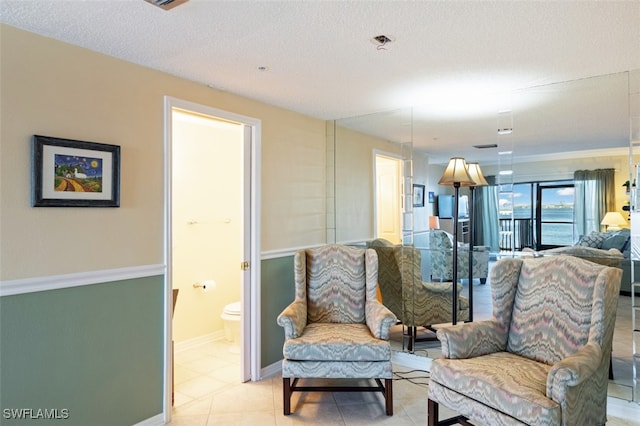 sitting room with a textured ceiling and light tile patterned floors