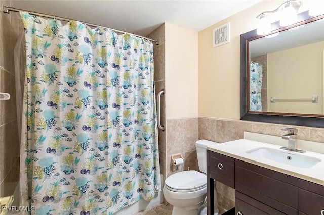 full bathroom with vanity, tile walls, shower / bath combo with shower curtain, and toilet