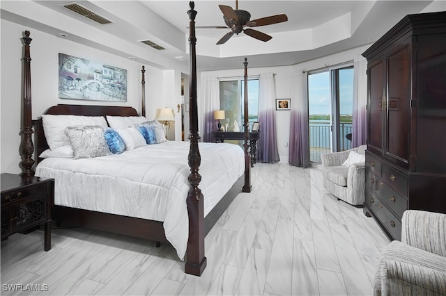 bedroom with ceiling fan, access to outside, and a tray ceiling