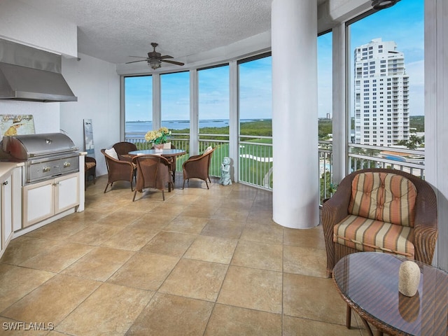 sunroom / solarium featuring a water view and ceiling fan