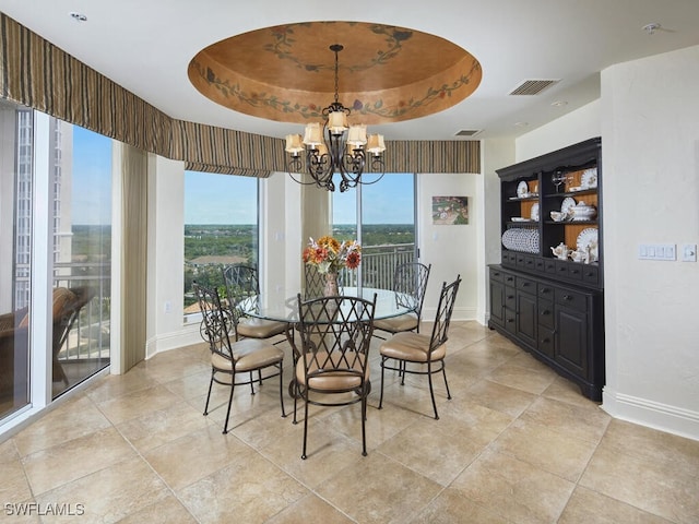 dining space with a raised ceiling and a chandelier