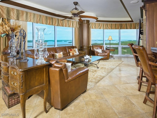 living room with a wealth of natural light, a water view, a tray ceiling, and ceiling fan