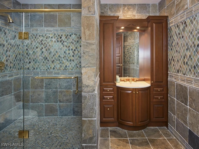 bathroom with tile walls, a stall shower, and vanity