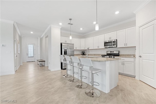 kitchen with white cabinets, ornamental molding, a breakfast bar, a kitchen island with sink, and stainless steel appliances