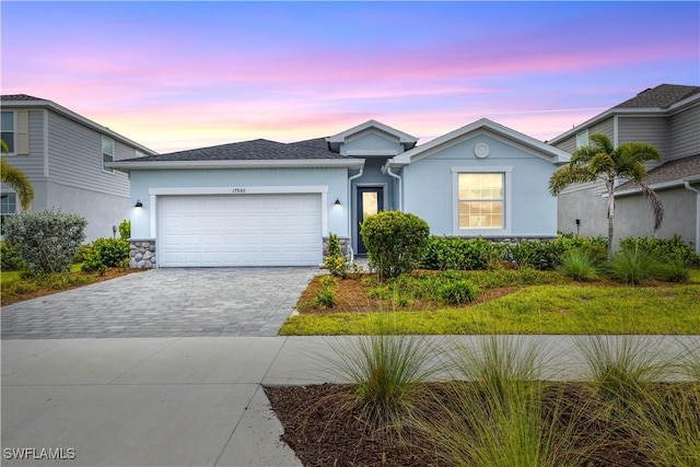 ranch-style house with a garage, decorative driveway, and stucco siding