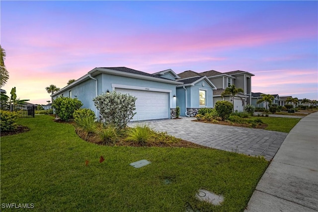 view of front of property with decorative driveway, stucco siding, a front yard, fence, and a garage