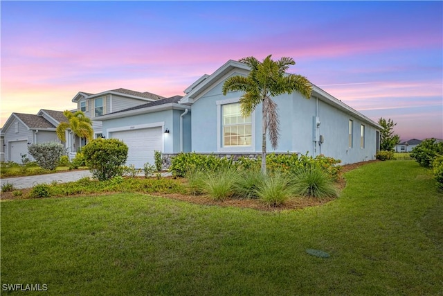 view of front of property with a garage, driveway, a front lawn, and stucco siding