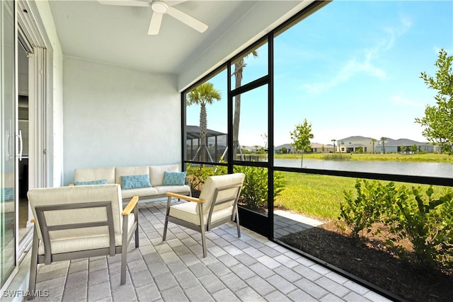 sunroom featuring ceiling fan and a water view