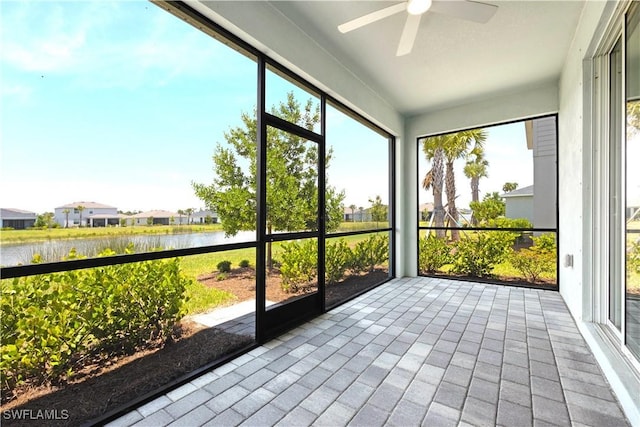 unfurnished sunroom featuring a ceiling fan, a healthy amount of sunlight, and a water view