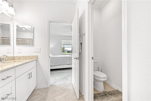 bathroom with baseboards, toilet, ensuite bathroom, tile patterned flooring, and vanity