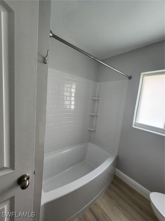 bathroom featuring tiled shower / bath combo, hardwood / wood-style flooring, and toilet