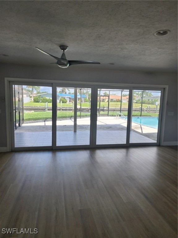 unfurnished room with ceiling fan, a textured ceiling, dark hardwood / wood-style flooring, and a wealth of natural light