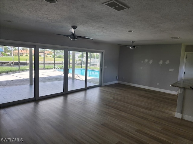 empty room with ceiling fan, a textured ceiling, and dark wood-type flooring