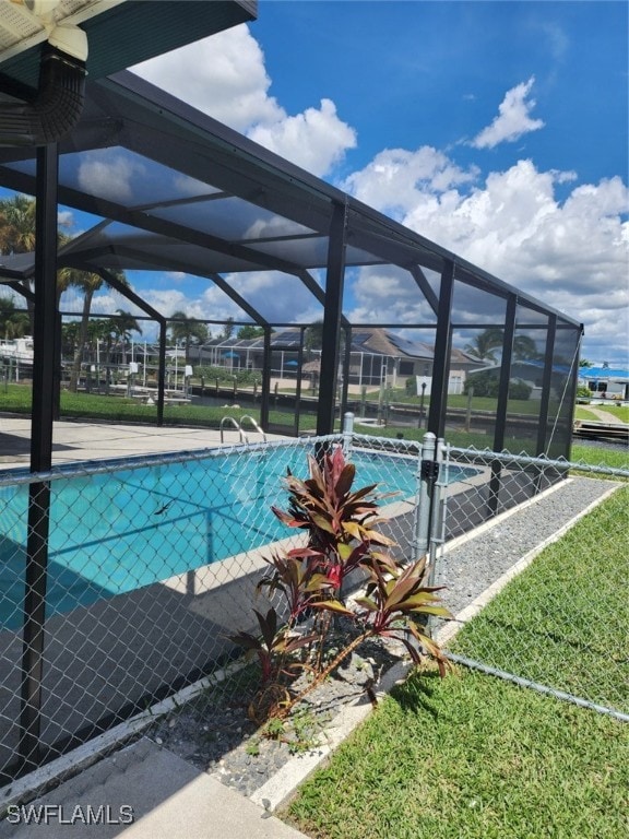 view of pool with a lawn and a lanai