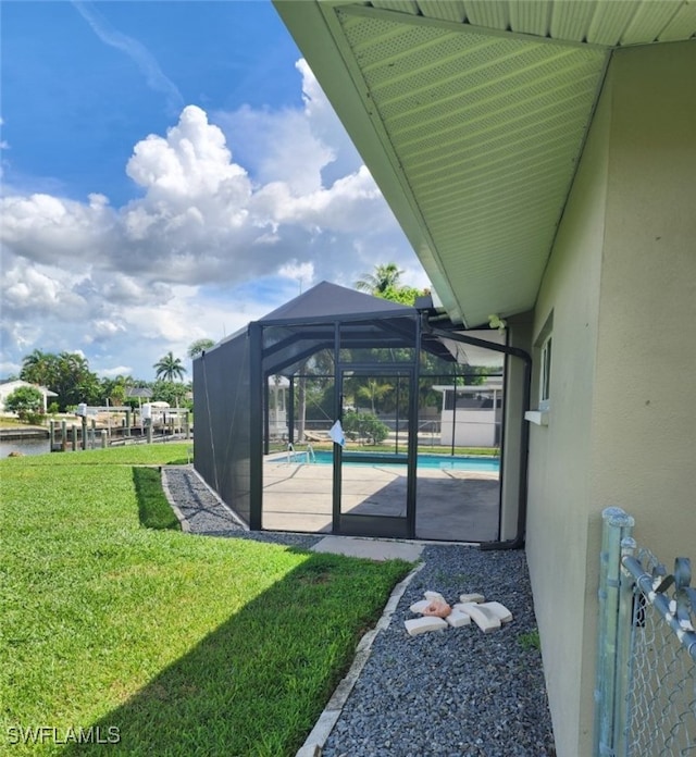 view of pool with glass enclosure and a lawn