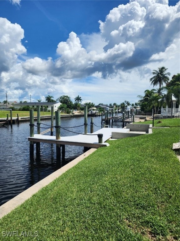 view of dock with a lawn and a water view