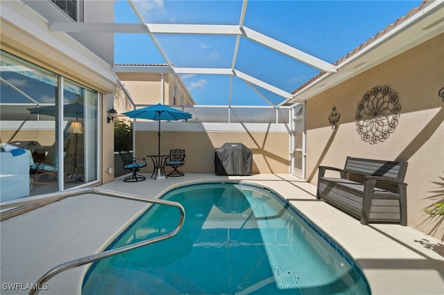 view of pool with a lanai, a grill, and a patio area