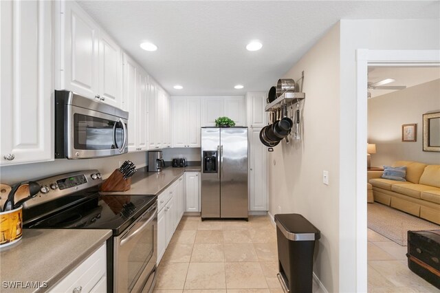 kitchen featuring white cabinets, appliances with stainless steel finishes, and light tile patterned flooring