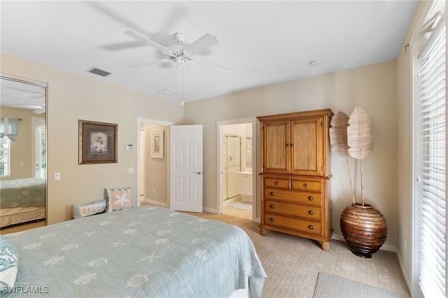 carpeted bedroom with ensuite bath, ceiling fan, and multiple windows