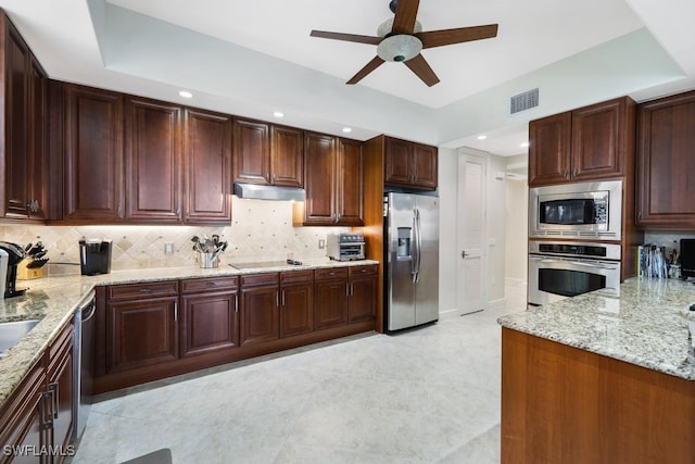 kitchen with light stone counters, stainless steel appliances, tasteful backsplash, visible vents, and under cabinet range hood