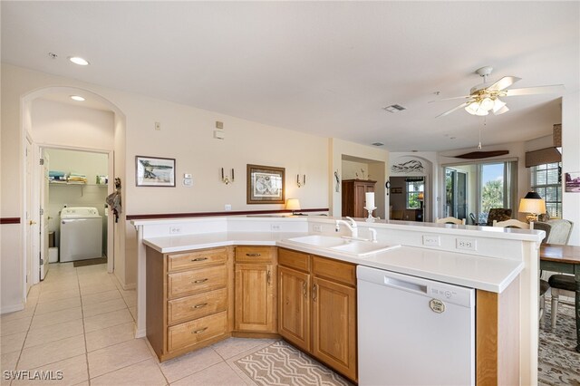 kitchen with white dishwasher, light tile patterned floors, sink, and washer / clothes dryer