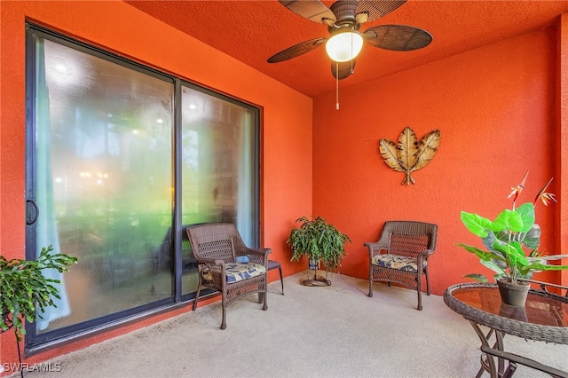 living area featuring ceiling fan, carpet floors, and a textured ceiling