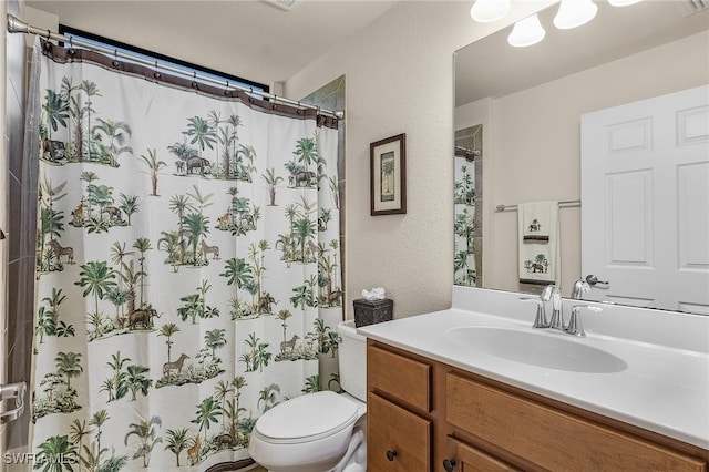 bathroom with curtained shower, vanity, and toilet