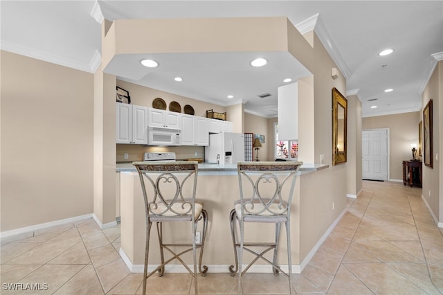 kitchen with light tile patterned flooring, white cabinetry, a kitchen bar, kitchen peninsula, and white appliances