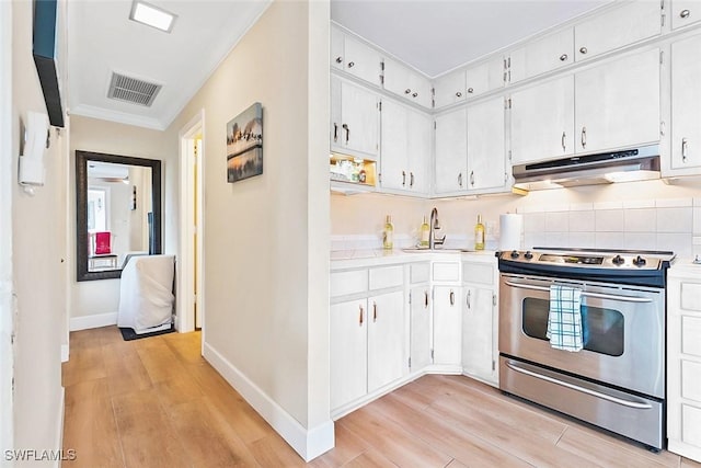 kitchen featuring stainless steel range with electric stovetop, white cabinetry, and sink