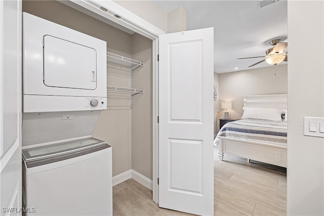 clothes washing area with stacked washer / dryer, light hardwood / wood-style floors, and ceiling fan