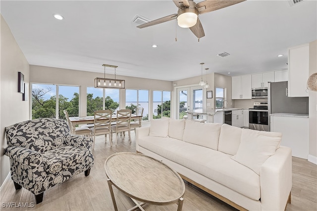 living room with light hardwood / wood-style floors, sink, and ceiling fan