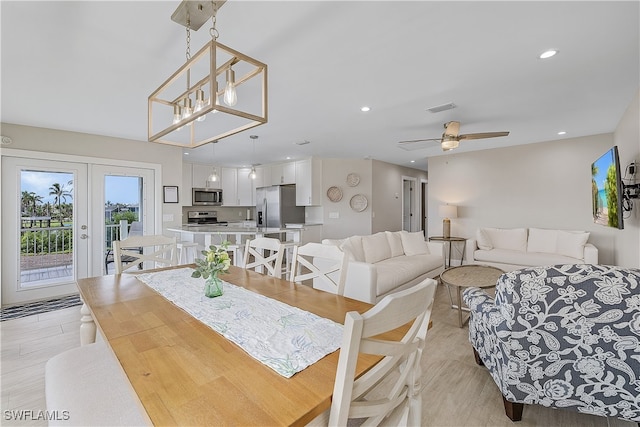 dining space featuring ceiling fan with notable chandelier and light hardwood / wood-style flooring