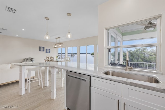 kitchen featuring pendant lighting, white cabinets, dishwasher, and light stone counters