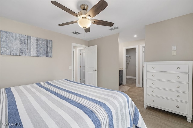 bedroom with light wood-type flooring, a spacious closet, ceiling fan, and a closet