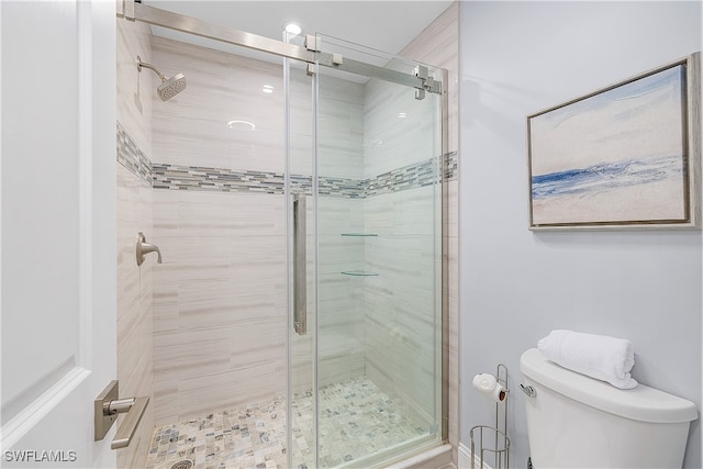 bathroom featuring a shower with door and toilet