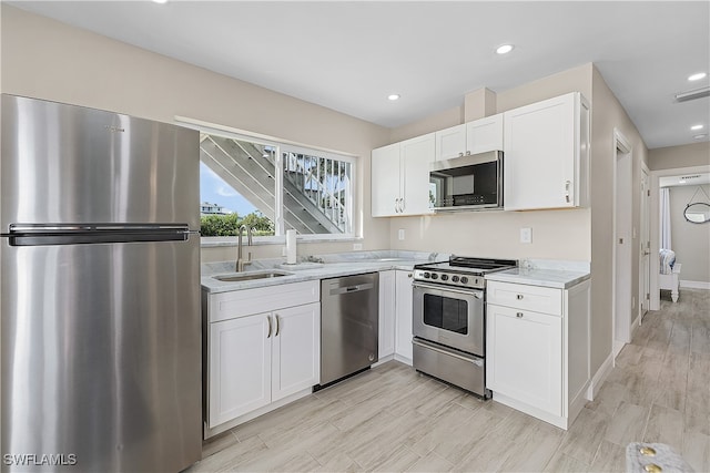 kitchen featuring light stone counters, light hardwood / wood-style floors, sink, white cabinetry, and stainless steel appliances