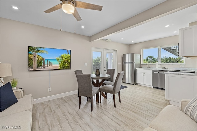 dining space featuring ceiling fan, sink, light hardwood / wood-style flooring, and french doors