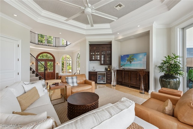 living room with ornamental molding, wine cooler, a raised ceiling, indoor bar, and ceiling fan