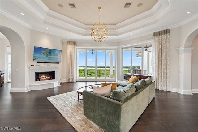 living room featuring dark wood-type flooring, a tray ceiling, and ornamental molding