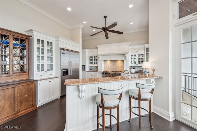 kitchen featuring white cabinetry, kitchen peninsula, premium appliances, and dark wood-type flooring